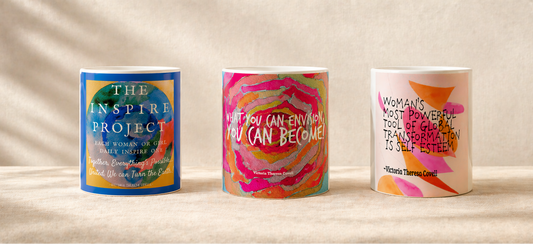 Three colorful mugs with motivational phrases on a wooden surface.
